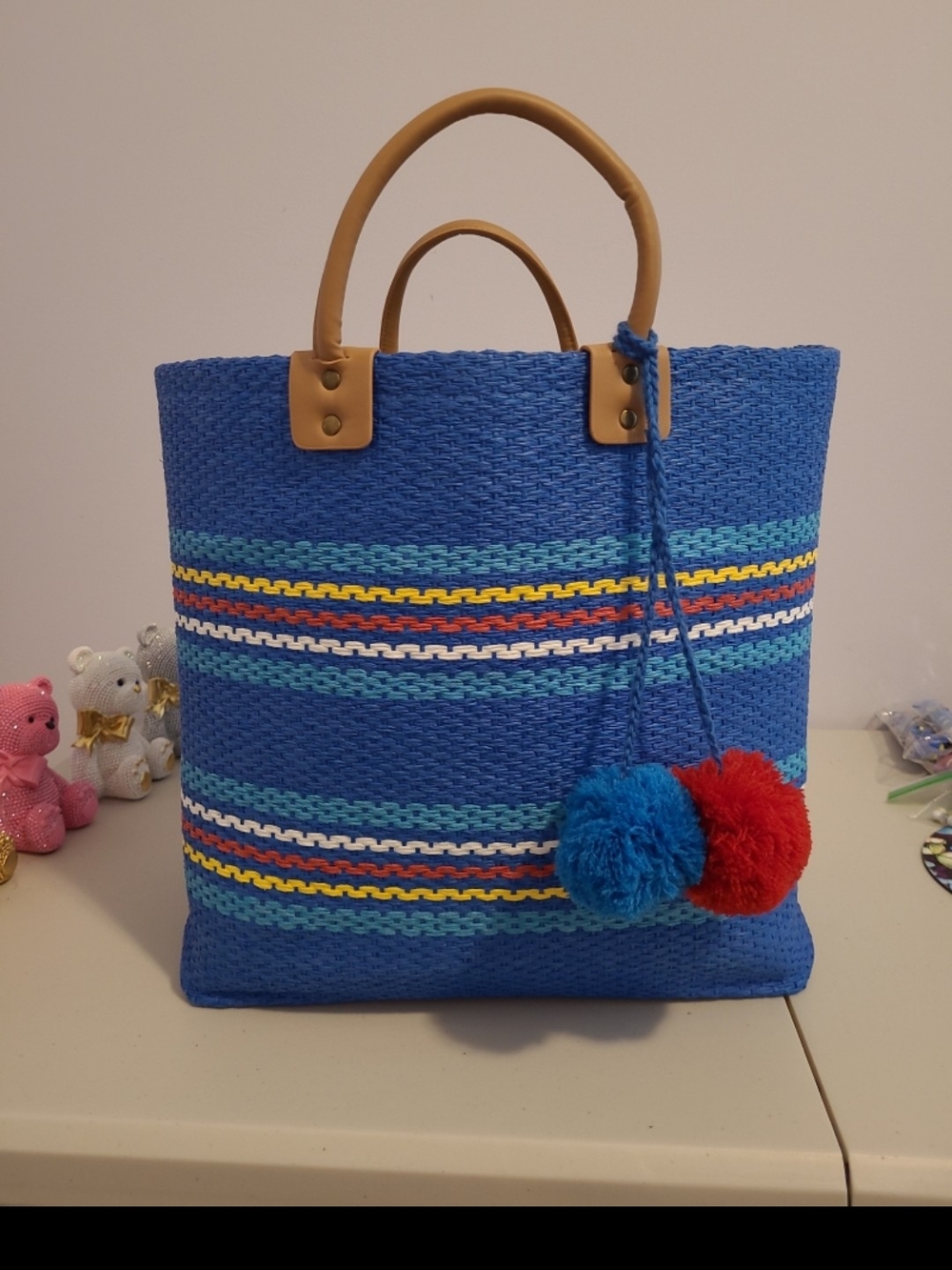 Colleen Lopez Blue Woven Beach Bag with Colorful Stripes and Pom-Pom Accents